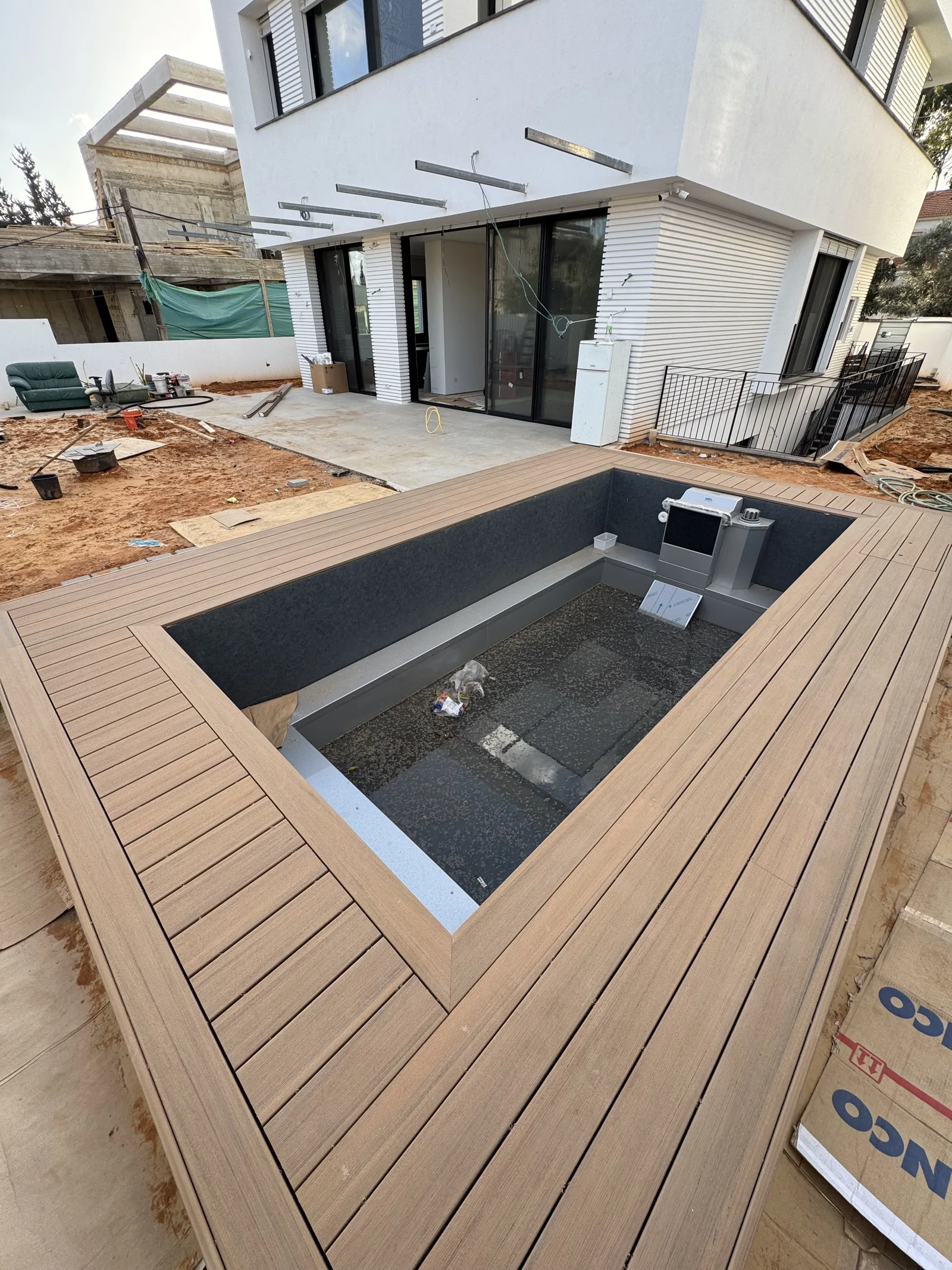 דק TimberTech בגוון קוקוס סביב בריכה ריקה במהלך עבודות בחצר